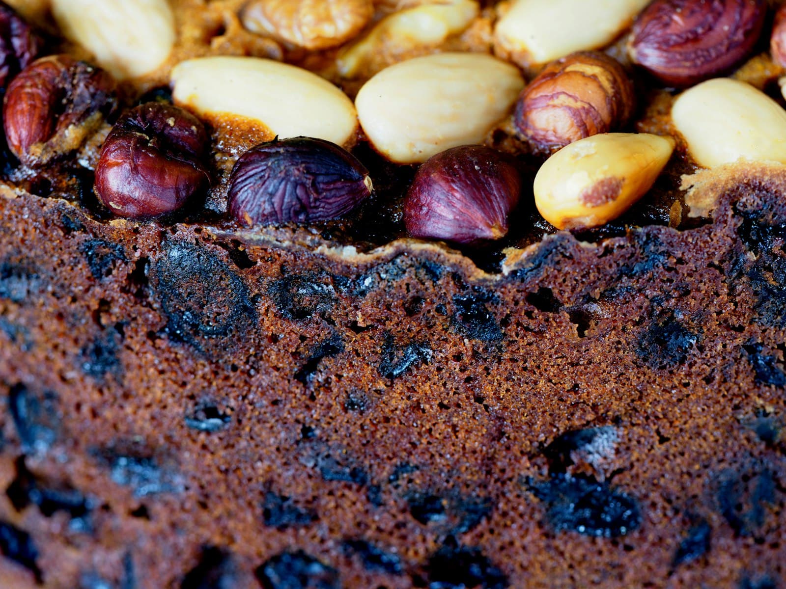 A dark, dense cross-section of Caribbean black cake, packed with fruit.