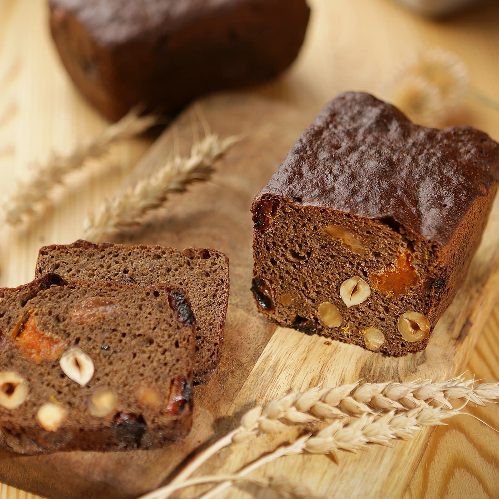 Slices of dark, spiced Caribbean fruit cake on kraft paper with ears of wheat.
