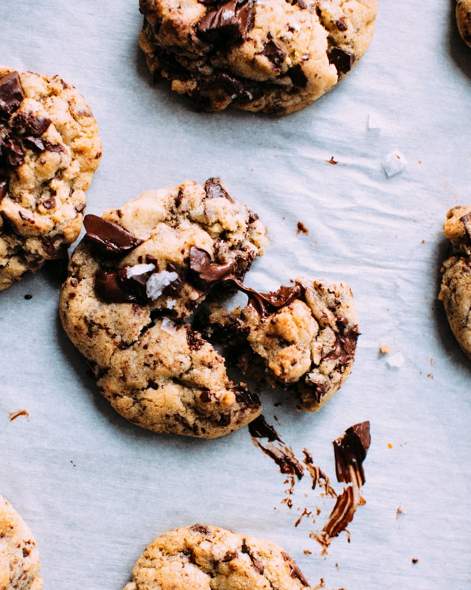 Overhead of gooey chocolate-chunk cookies with melted chocolate and flaky salt.
